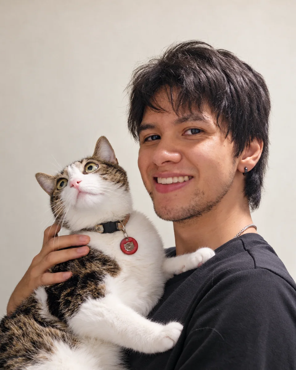 Santiago smiling with his cat Ahru in his arms.
